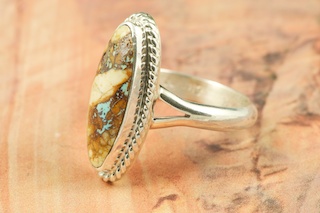 Genuine Boulder Turquoise set in Sterling Silver Ring. The cabachon is Boulder Turquoise, you can see the veins of Turquoise running through the host rock. The Boulder Turquoise Mine is located in northeast Nevada. It was discovered in 1970 by a Shoshone sheep herder. Production is small due to the remote location and winter weather. Boulder Turquoise is valued for both it's beauty and rarity. Every stone is unique. Created by Navajo Artist Arkie Nelson. Signed by the artist.